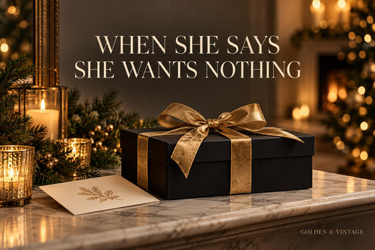 Black gift box with antique-gold ribbon beside a cream card in a warm Christmas setting
